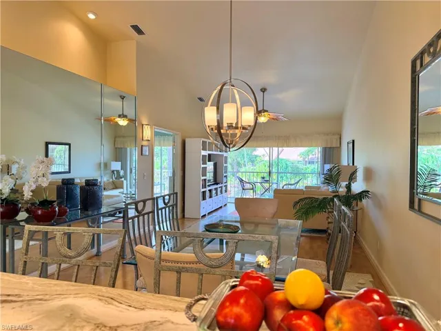 View from Kitchen bar into the Living room featuring a ceiling fan, hanging lights, plenty of natural light, and lofted ceiling
