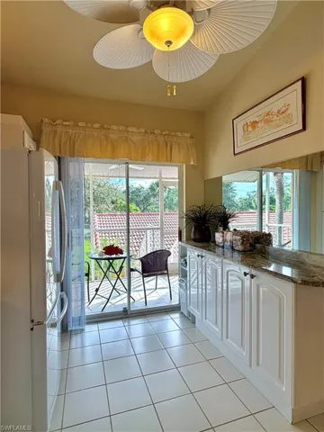 Kitchen,  light tile patterned floors, stone countertops, and white cabinets
