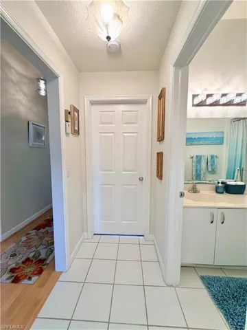Doorway to guestroom/office featuring a textured ceiling and tile patterned flooring