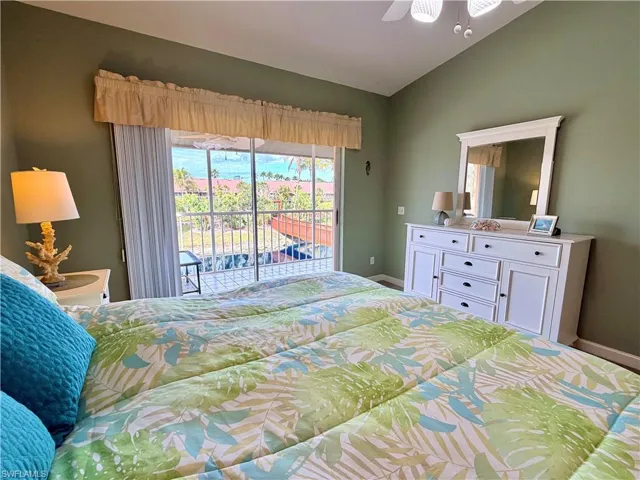 Bedroom with access to back balcony, lofted ceiling, and a ceiling fan