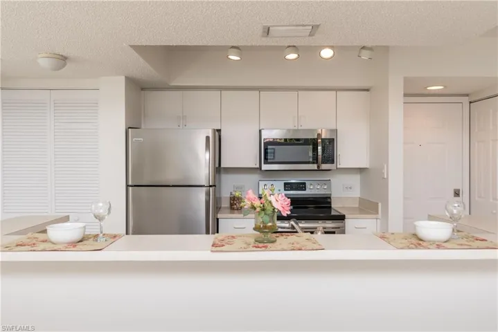 Kitchen with white cabinetry, stainless steel appliances, and a textured ceiling