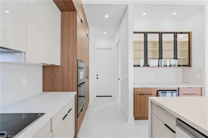 Kitchen featuring black electric cooktop, double wall oven, light tile patterned floors, white cabinets, and dishwasher