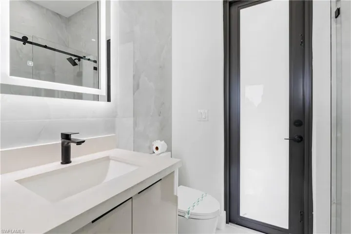 Bathroom featuring toilet, vanity, and an enclosed shower