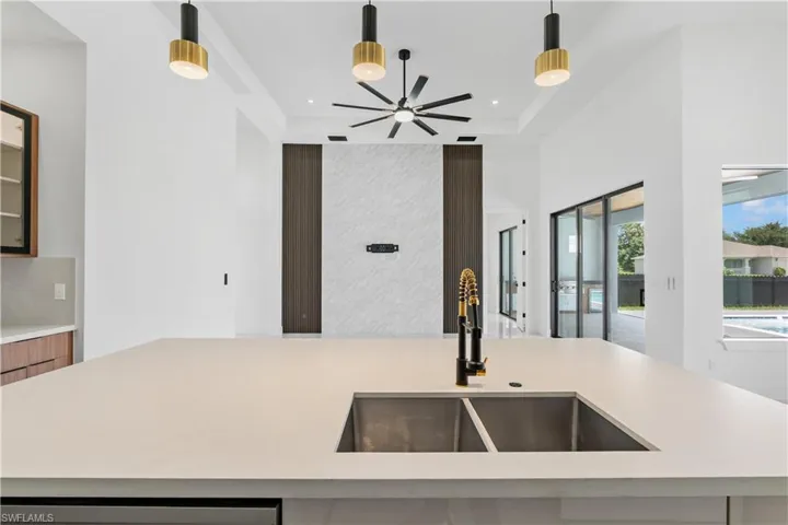 Kitchen featuring ceiling fan, decorative light fixtures, sink, and a raised ceiling
