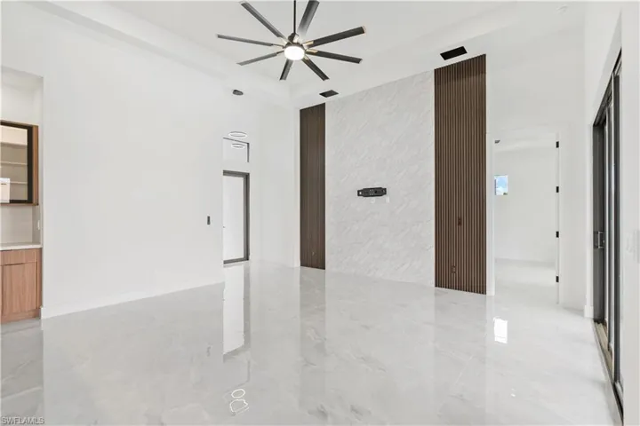 Unfurnished room featuring a high ceiling, ceiling fan, and light tile patterned floors