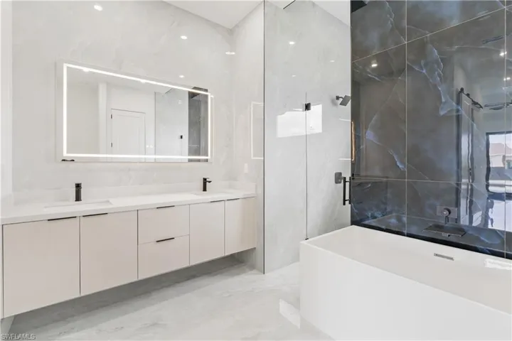 Bathroom with tile walls, tile patterned floors, and double sink vanity