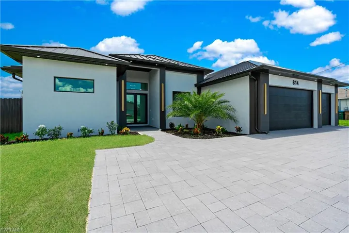 View of front of property featuring a garage and a front lawn