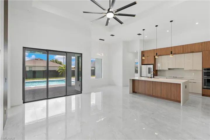 Kitchen featuring white cabinetry, ceiling fan, sink, light tile patterned floors, and a kitchen island with sink