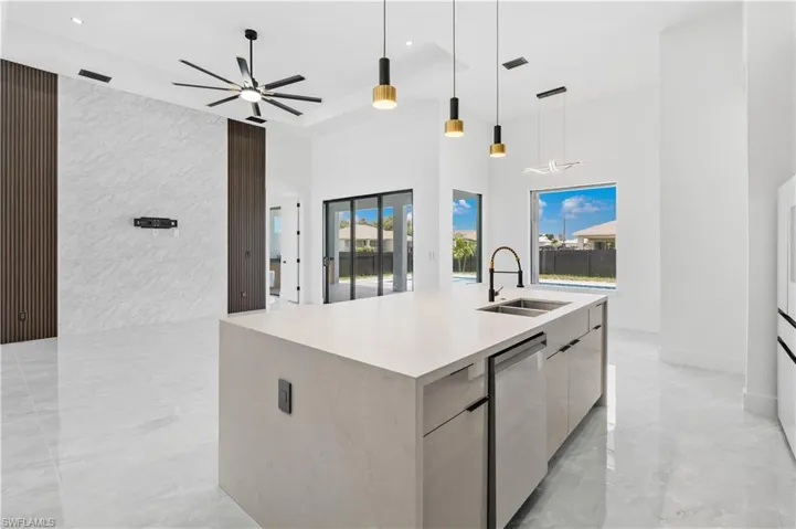 Kitchen featuring sink, a large island with sink, decorative light fixtures, and a wealth of natural light