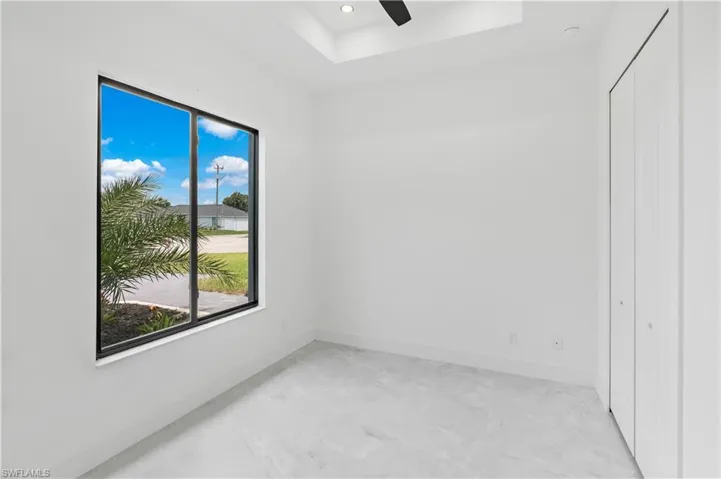 Unfurnished bedroom featuring a closet, ceiling fan, and a raised ceiling