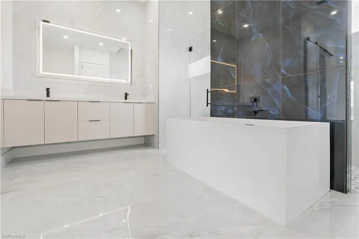 Bathroom featuring vanity, walk in shower, tile patterned flooring, and tile walls