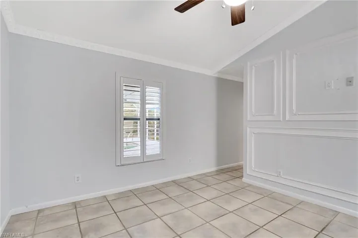 Master bedroom with ceiling fan, lofted ceiling, crown molding, and light tile patterned floors