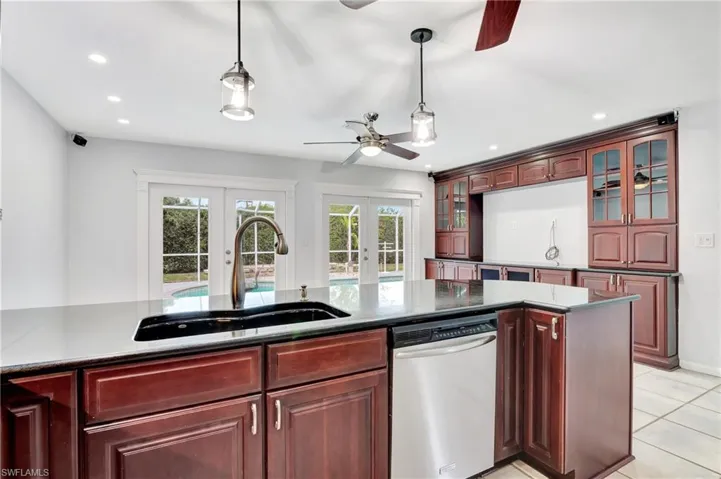 Kitchen featuring french doors, dishwasher, hanging light fixtures, glass insert cabinets, and  wood finish cabinets