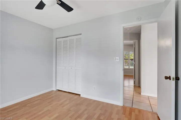 Unfurnished bedroom featuring light wood-style flooring, a closet, and a ceiling fan.
