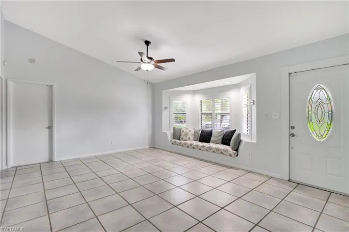 Entrance foyer with lofted ceiling, a ceiling fan, and light tile patterned flooring