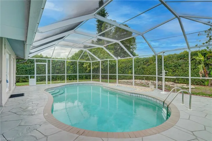 Outdoor pool featuring a sunroom,  screen enclosure, and a patio area.