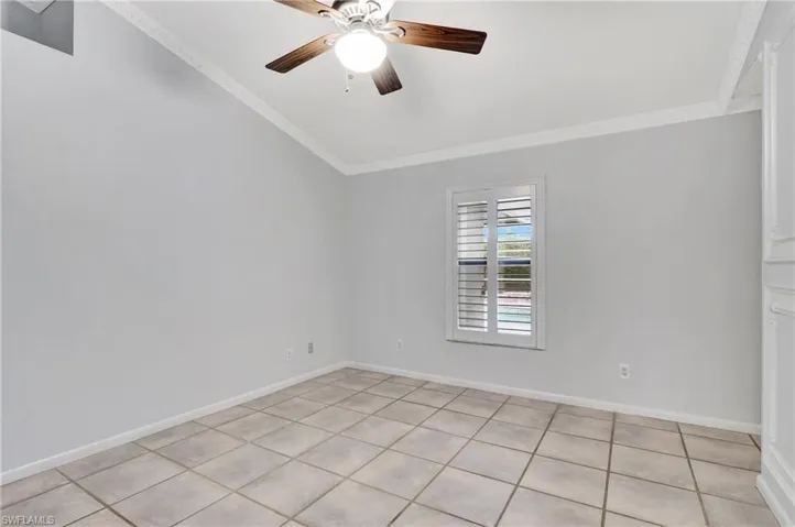Master bedroom featuring a ceiling fan, crown molding, and light tile patterned floors.