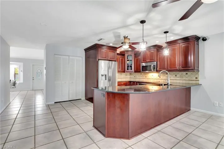 Kitchen featuring a peninsula, stainless steel appliances, ceiling fan, and decorative light fixtures