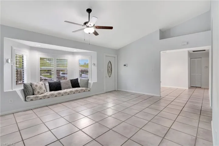 Unfurnished living room with ceiling fan, light tile patterned flooring, and lofted ceiling.