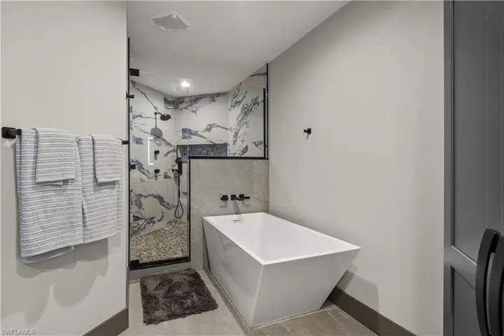Master Bathroom featuring a freestanding bath and a marble finish shower