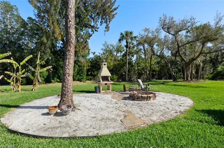 View of play area featuring an outdoor fire pit and a lawn