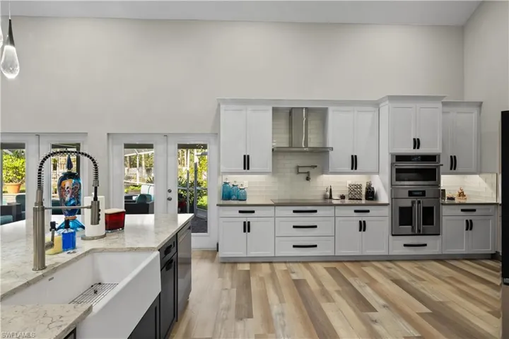 Large Kitchen perfect for Entertaining that features a stainless steel double oven, a farmer's sink and wall chimney range hood