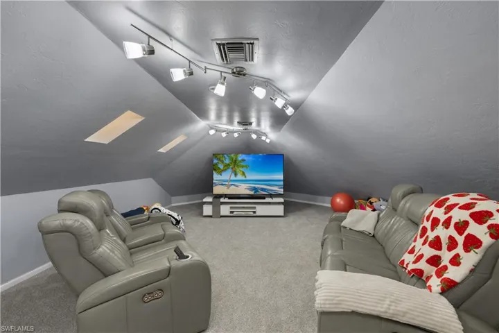 Carpeted home theater room with vaulted ceiling
