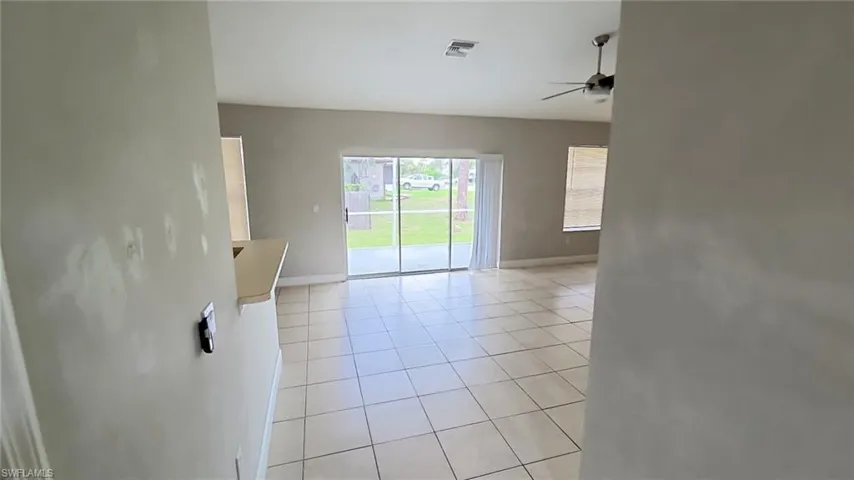 Open-concept living space with tile flooring throughout, a ceiling fan, and sliding glass doors leading to an outdoor area