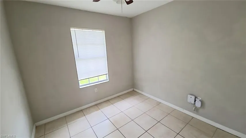 Neutral-toned interior room featuring tile flooring, a window with horizontal blinds, and a ceiling fan
