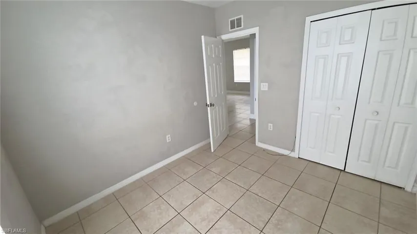 Neutral-toned tiled flooring throughout, complemented by light gray wall finishes and white baseboards