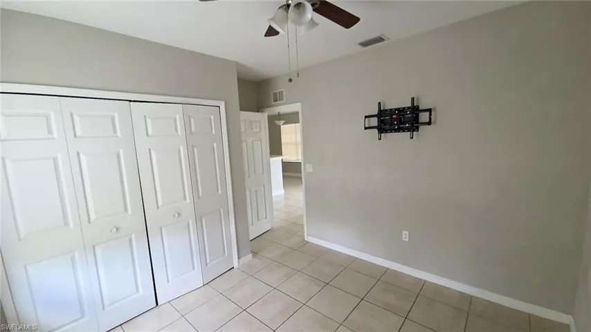 Neutral toned interior room featuring tile flooring and a ceiling fan