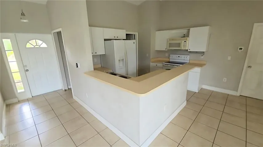Kitchen featuring white cabinetry, light countertops, and tile flooring