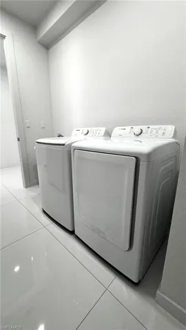 Washroom featuring washer and dryer and light tile patterned floors