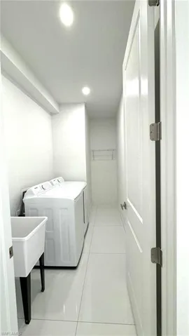 Washroom with separate washer and dryer and light tile patterned floors