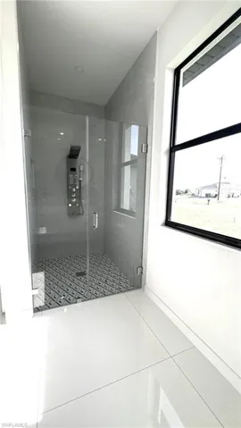 Bathroom with a shower with shower door and tile patterned flooring