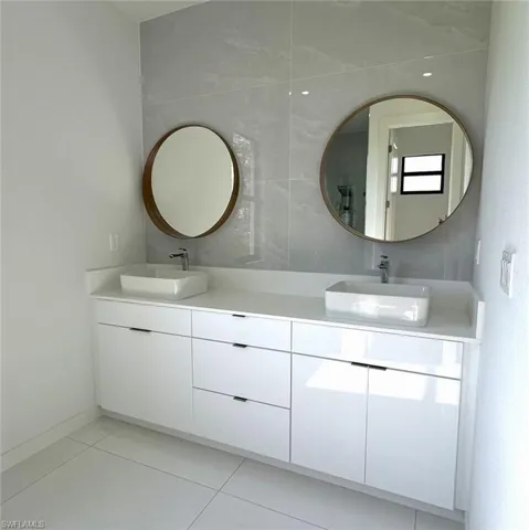 Bathroom with tile walls, dual vanity, and tile patterned floors