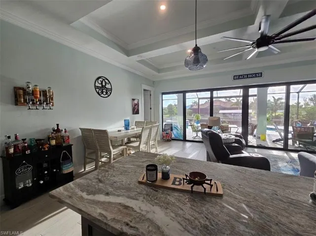 Dining room featuring ceiling fan, ornamental molding, a tray ceiling
