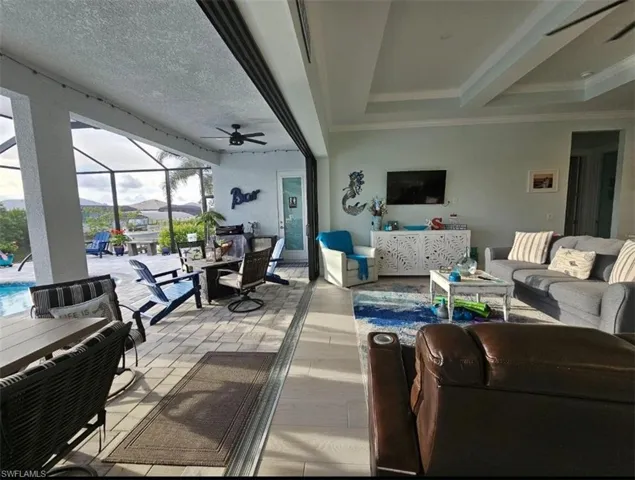 Great room featuring ceiling fan, Tray ceiling (11ft) with crown molding, and Porcelain Plank Floors, 10ft Ceiling Heights throughout, 24ft Pocketing Sliding Glass Doors to Lanai.