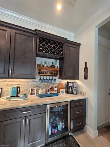 Bar featuring beverage cooler, granite backsplash,