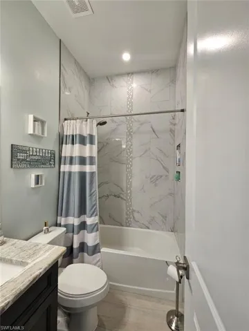 Guest Full bathroom with vanity, shower / bath combination with curtain, and toilet