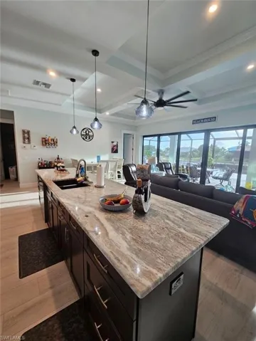 Kitchen Island-featuring a 13ft center island, ceiling fan, sink, pendant lights, extra drawer banks, trash pullout.