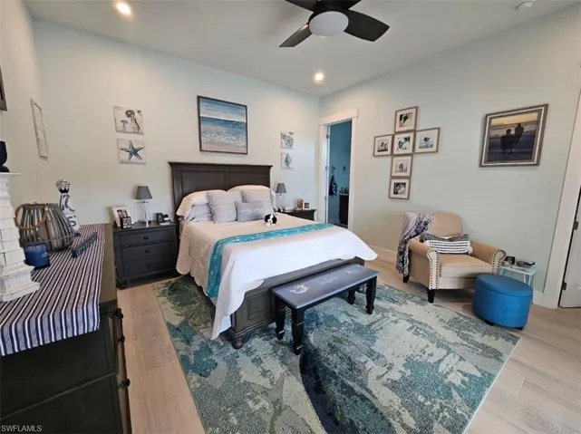 Bedroom with connected bathroom, ceiling fan, and light hardwood / wood-style floors