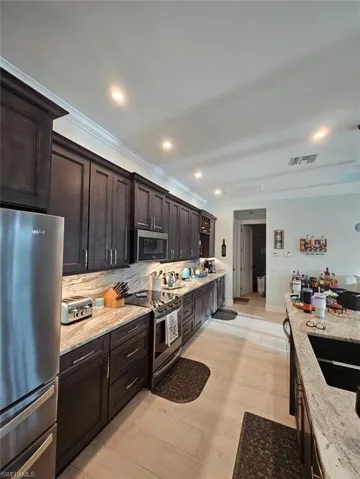 Kitchen with appliances with stainless steel finishes, 42" upper Gray/brown cabinets, Full Granite Backsplash, under cabinet lighting and outlets