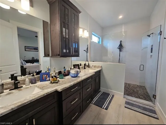 Bathroom with a shower with shower door, Porcelain Plank flooring, and double sink vanity