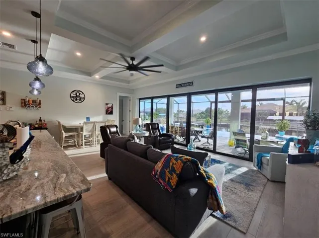 Great room featuring ceiling fan, Tray ceiling (11ft) with crown molding, and Porcelain Plank Floors, 10ft Ceiling Heights throughout, 24ft Pocketing Sliding Glass Doors to Lanai.