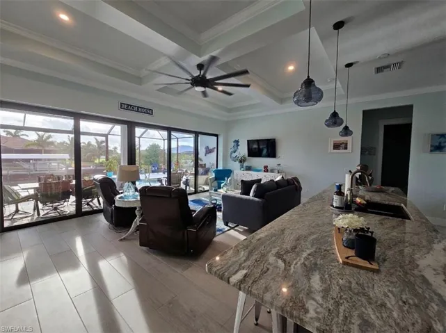 Great room featuring ceiling fan, Tray ceiling (11ft) with crown molding, and Porcelain Plank Floors, 10ft Ceiling Heights throughout, 24ft Pocketing Sliding Glass Doors to Lanai.