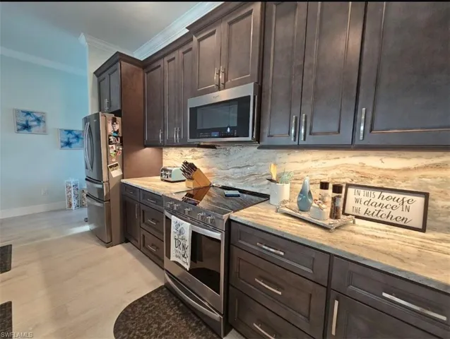 Kitchen with crown molding, stainless steel appliances, Kitchen with appliances with stainless steel finishes, 42" upper Gray/brown cabinets, Full Granite Backsplash, under cabinet lighting and outlets