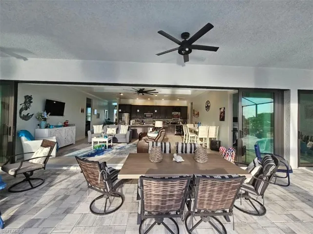 Outdoor Living to Great room featuring ceiling fan, Tray ceiling (11ft) with crown molding, and Porcelain Plank Floors, 10ft Ceiling Heights throughout, 24ft Pocketing Sliding Glass Doors to Lanai.