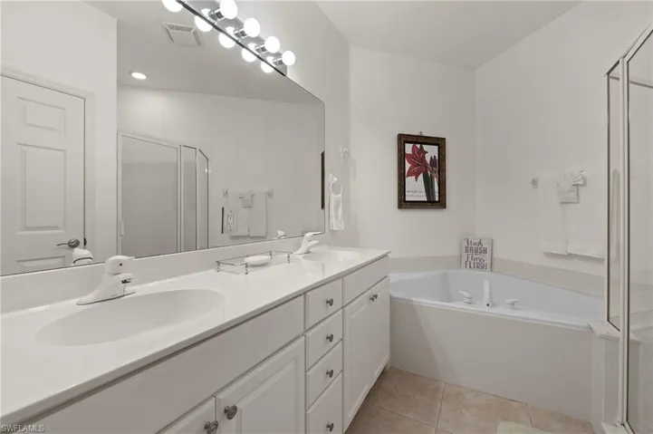 Bathroom featuring plus walk in shower, tile patterned flooring, and vanity