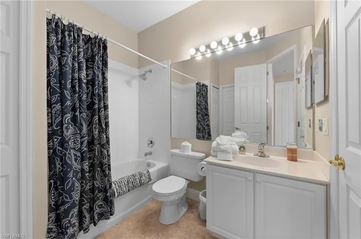 Full bathroom with vanity, toilet, shower / tub combo with curtain, and tile patterned flooring